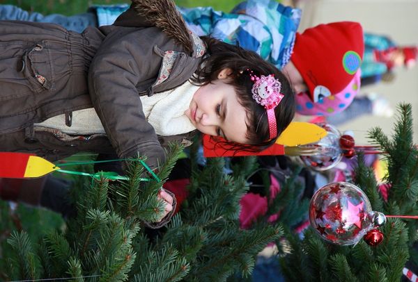 Ein Kind schmückt mit Hingabe den Weihnachtsbaum vorm Rathaus