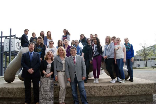 Das Bild zeigt Bürgermeister Werner Arndt (vorne rechts) mit den Schülerinnen und Schülern aus England und ihren Lehrern Vaughan Smith, Julie Howarth und Elke Freeman (von vorne links) vor der Naturmaschine auf dem Creiler Platz.