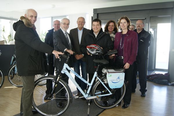 Bürgermeister Werner Arndt (mit Helm in der Hand) freut sich über die RWE-Elektrofahrräder, die Maria Allnoch (re.) der Stadt Marl im Namen von RWE übergeben hat.