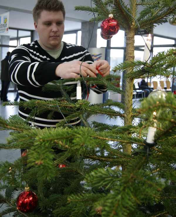 Manuel Helbig schnürt rote Bänder zu weihnachtlichen Schleifen.