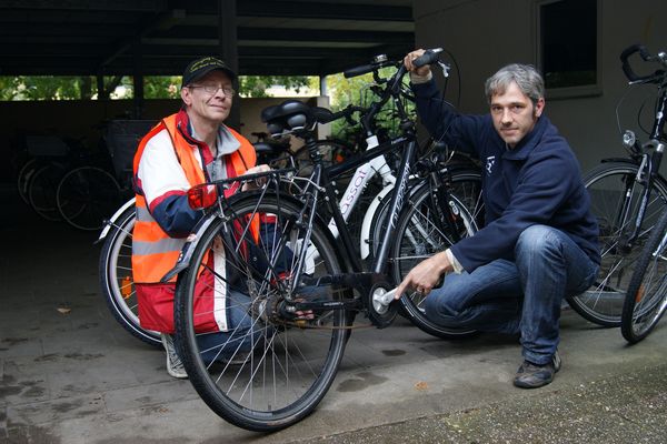 Fahrradwächter Udo Frerich und Zweiradexperte Marcel Koritnik betrachten ein Fahrrad in der Fahrradwache am ASGG.