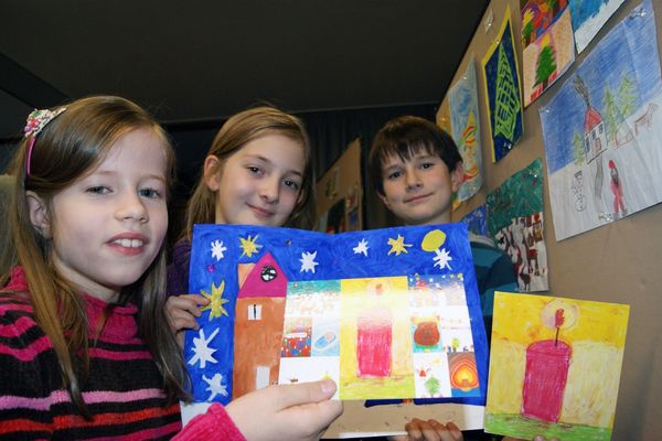 Die Sieger des diesjährigen Weihnachts-Malwettbewerb: Flora Speikamp (Sonderpreis), Lea Golpon (2. Platz) und der Sieger Tim Steinmetz (v.l.). Rechts unten im Bild das Gewinnermotiv "Kerze"