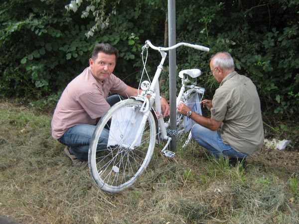 Jörg Teichert (l.) und Udo Klein von der Direktion Verkehr der Polizei Marl bei der Montage neuer Hinweisschilder an den Weißen Fahrrädern.