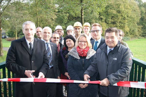 Bürgermeister und Bergwerkschef durchschneiden das Absperrband und geben die neue Fußgängerbrücke frei.