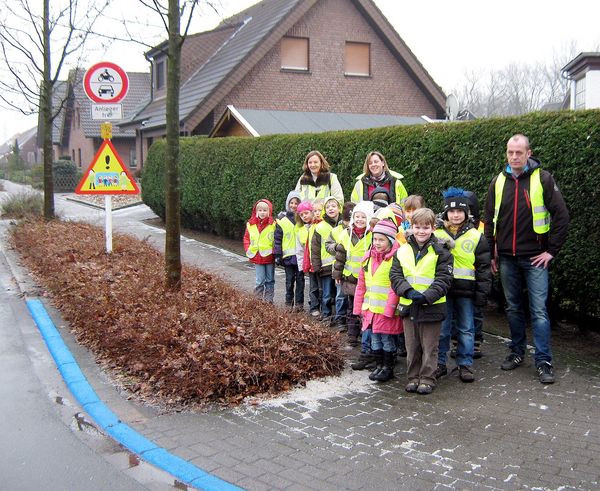 Das Bild zeigt die Erstklässler des Walking Bus mit den Eltern, die die Rolle des ehrenamtlichen  „Fahrers“ und „Schaffners“ übernommen haben