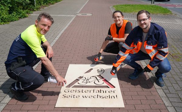 Polizeihauptkommissar Karsten Quante (l.), Radverkehrskoordinator Marc Vogel (r..) und Werkstudent Benedict Ernst sprühen den ersten Warnhinweis auf die Bergstraß;e. Fotos: Stadt Marl / Pressestelle